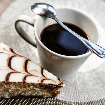 Ein Stück Kuchen und eine Tasse Kaffee mit Kaffeelöffel.