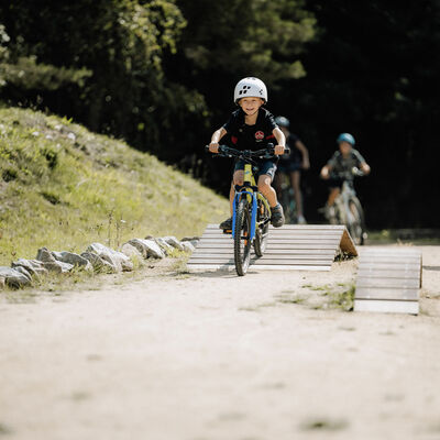 Kinder fahren mit dem Rad über verschiedene Hindernisse aus Holz.