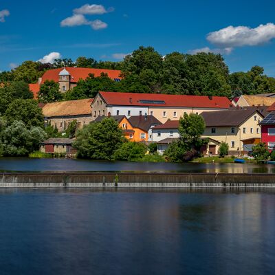 Blick auf Schloss Fronberg. Es sind noch weitere Häuser in bunten Farben und der Fluss Naab zu sehen.