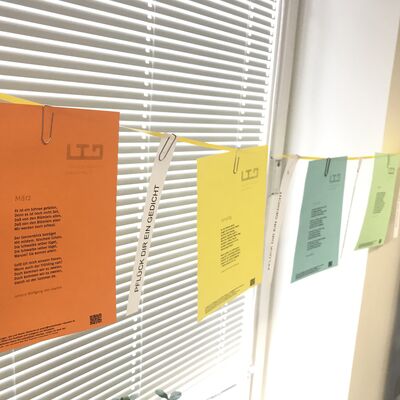 Bild vergrößern: Gedichte auf Papier wurden an einer Leine mit Klammern aufgehängt. Titel: Pflück dir dein Gedicht