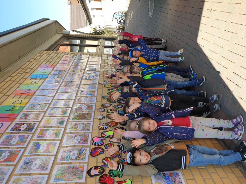 Mehrere Kinder vor einer Wand mit Bildern und Hand-Abdrcken.