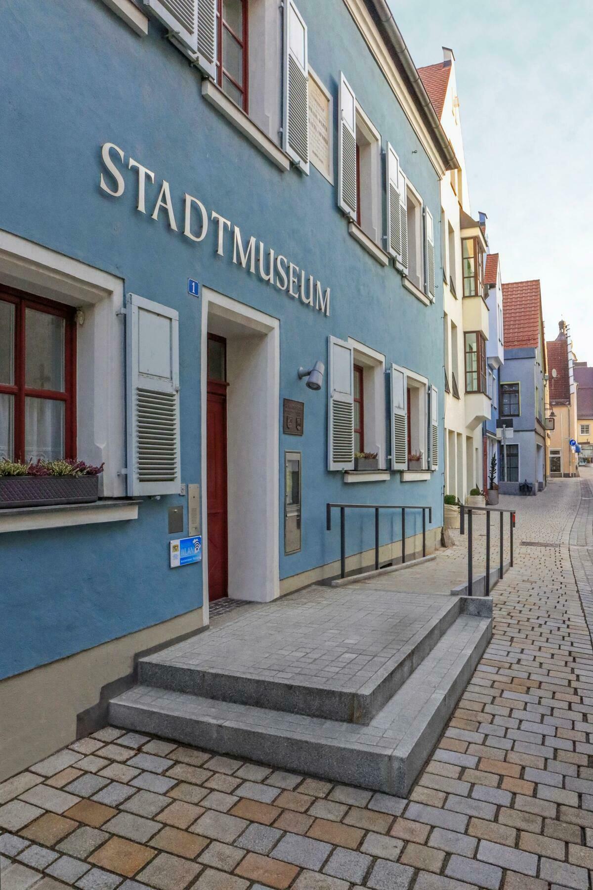 Bild vergrößern: Seitliche Aufnahme von der blauen Fassade des Stadtmuseums. Über der hölzernen Eingangstür hängt in silbernen Großbuchstaben der Schriftzug "Stadtmuseum"