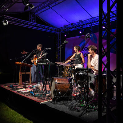 Seitliche Ansicht auf die Band, die von Scheinwerfern beleuchtet wird, bei Nacht.