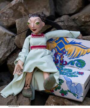 Bild vergrößern: weibliche Marionettenpuppe sitzt auf einem kleinem Sofa