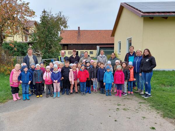 Bild vergrößern: Das Bild zeigt eine Gruppe von Kindern aus einem Kindergarten und Erzieherinnen. Vor einem Bauernhof.