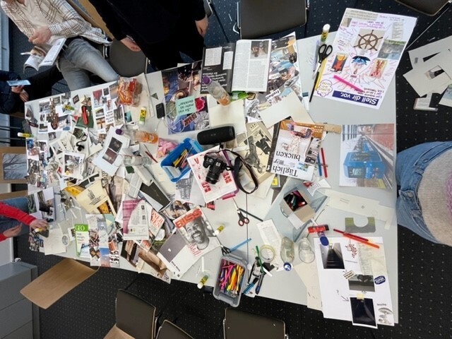 Ein Tisch auf dem Viele verschiedene Zeitschriften, Programmhefte, Fotos und allerlei buntes Papier liegen.