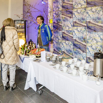Blick auf das Festivalcafé. Auf zwei Tischen sind Kaffeetassen und verschiedene Snacks aufgebaut.