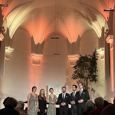 Die sechs Musikerinnen und Musiker des Vokalensembles StimmGold stehen festlich gekleidet auf der Bühne.