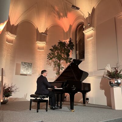 Der Pianist Christian Seibert sitzt auf der Bühne der Spitalkirche an einem offenen schwarzen Flügel.