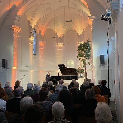 Der Pianist Christian Seibert sitzt auf der Bühne der Spitalkirche an einem offenen schwarzen Flügel.