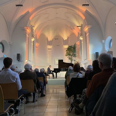 Der Pianist Christian Seibert sitzt auf der Bühne der Spitalkirche an einem offenen schwarzen Flügel.
