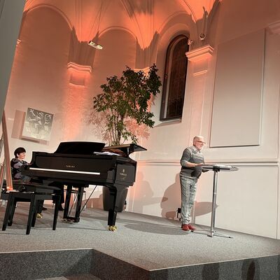 Der Künstler Peter Nüesch steht an einem Stehtisch auf der Bühne der Spitalkirche.