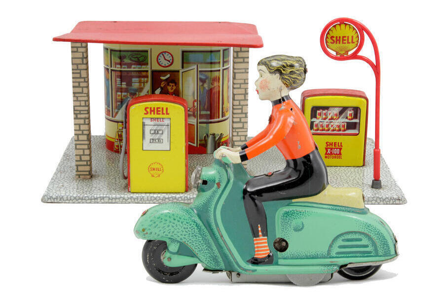 Ein altes Blechspielzeug.
Es zeigt einen Rollerfahrer an einer Tankstelle