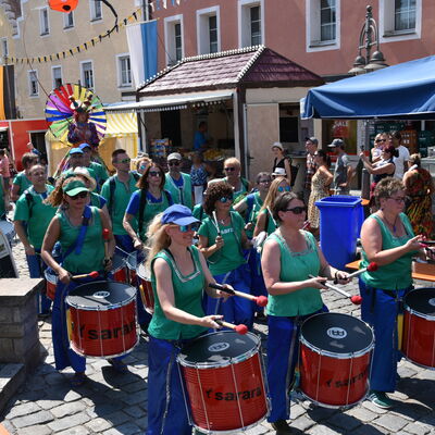 Bild vergrößern: Die grün-blau gekleideten Mitglieder der Trommelgruppe Sarará ziehen durch das Bürgerfest.