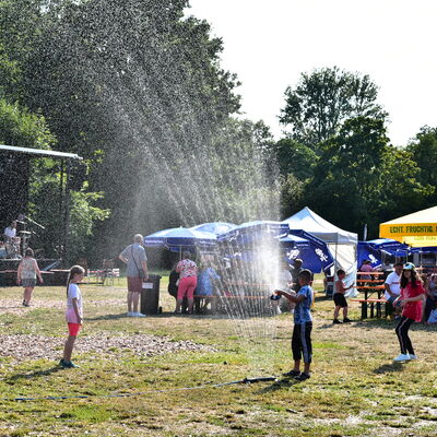 Bild vergrößern: Auf dem Festplatz im Stadtpark spielen Kinder unter einem Rasensprenger.