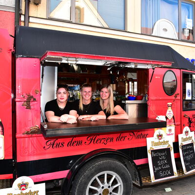 Bild vergrößern: Die drei Bedienungen des roten "Bierautos" vom Haselbacher Kirchawirt schauen aus der Verkaufsklappe