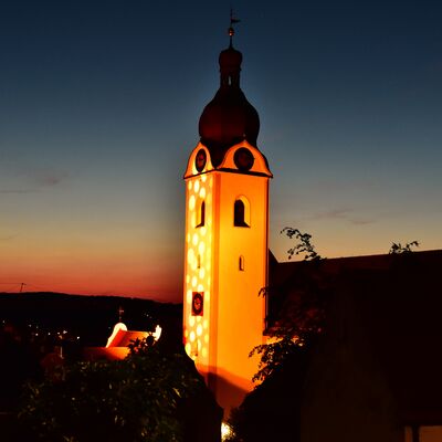 Bild vergrößern: Der bunt beleuchtete Turm der St.Jakobs-Kirche im letzten Abendrot.