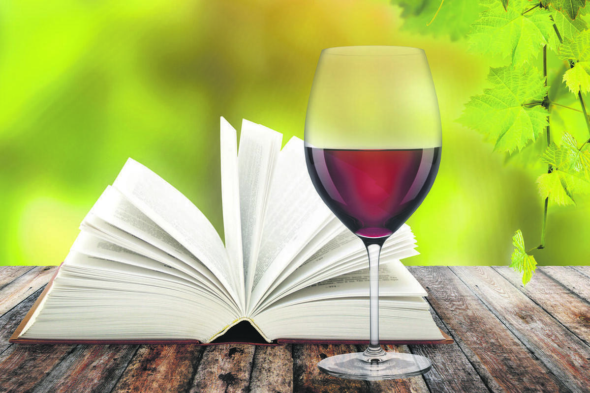 Bild vergrößern: Offenes Buch und ein Glas Wein stehen auf einem Holztisch