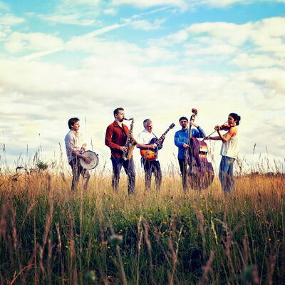 Bandfoto der 5 Bandmitglieder in einem Feld