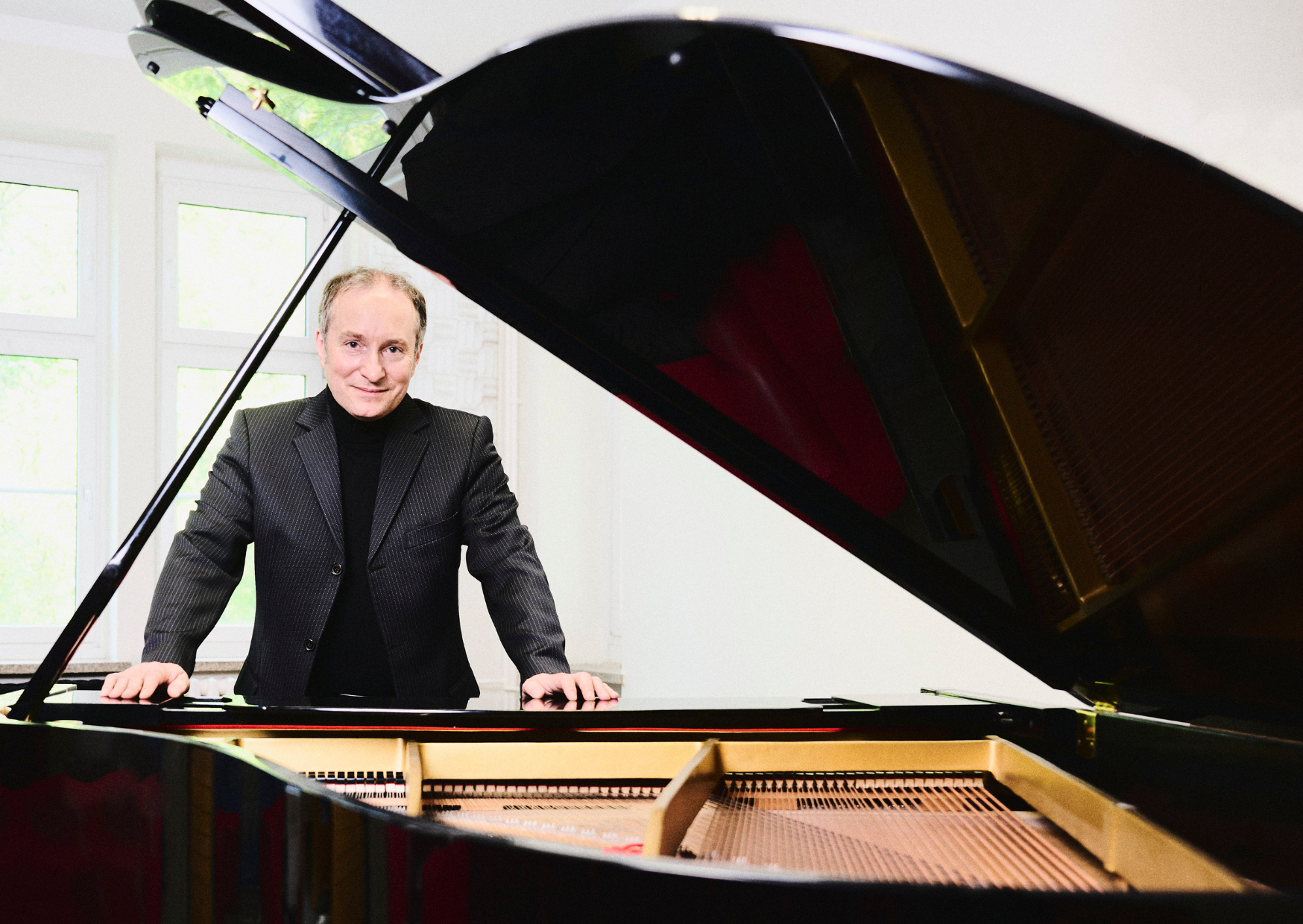Bild vergrößern: Der Pianist Christian Seibert steht vor einem geöffneten schwarzen Flügel