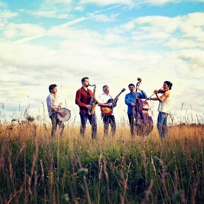 Bild vergrößern: Die Musiker des Balkon Jazz Ballett stehen auf einer Wiese und spielen ihre Instrumente.
