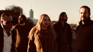 Die f&uuml;nf Musikerinnen und Musiker der Band John Garner vor dem Augsburger Fernsehturm im Abendlicht. 