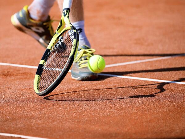 Ein Tennisschläger mit einem Ball auf einem Tennisplatz
