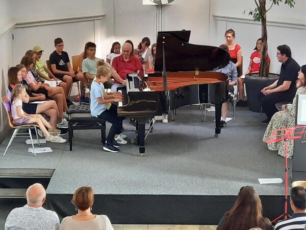 Schler der Musikschule Schwandorf sitzen auf der Bhne vor dem Klavier
