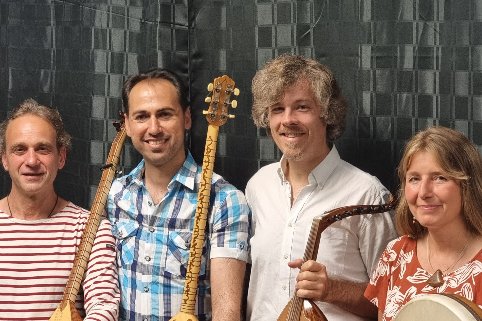 Bild vergrößern: Foto: Die Künstler:innenn der Band BARAN mit orientalischen Musikinstrumenten stehen nebeneinander in einer Reihe und lachen.