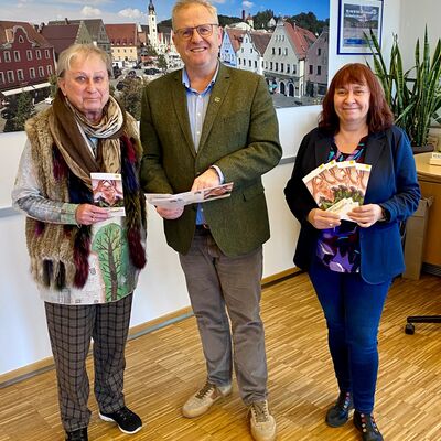 Zwei Frauen und ein Mann präsentieren das Seniorenprogramm der Stadt.