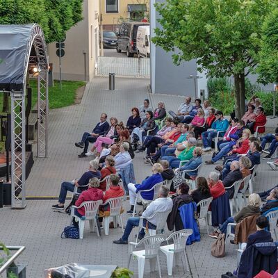 Bild vergrößern: Luftaufnahme des Spitalgartens. Menschen sitzen mit Abstand vor der Open-Air-Bühne. Abendliche Stimmung.