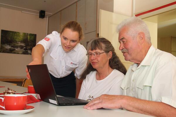 Eine Junge Dame erklrt zwei lteren Personen etwas am Laptop