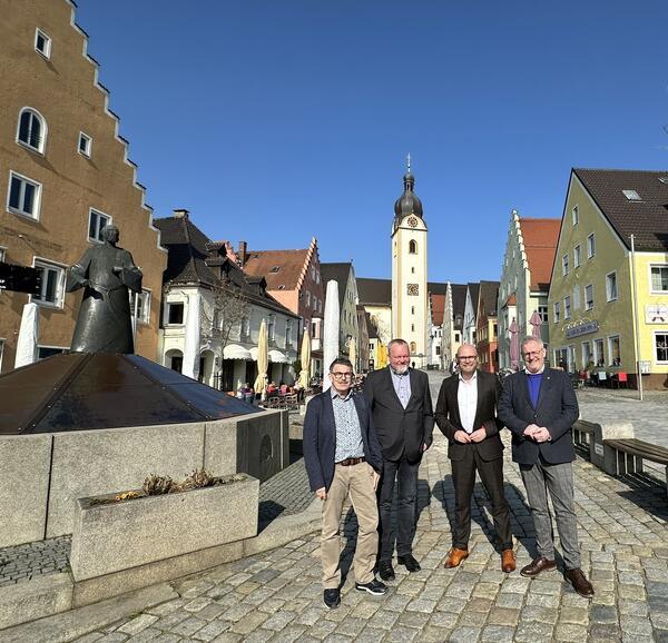 Vier Männer auf einem Marktplatz.