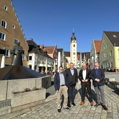 Bild vergrößern: Vier Mnner auf einem Marktplatz.