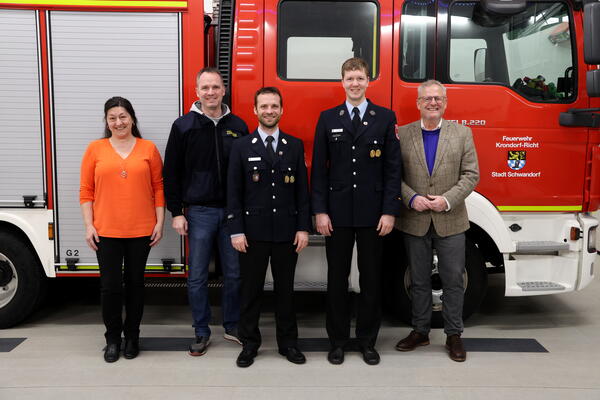 Eine Frau und vier Mnner vor einem Feuerwehrauto.