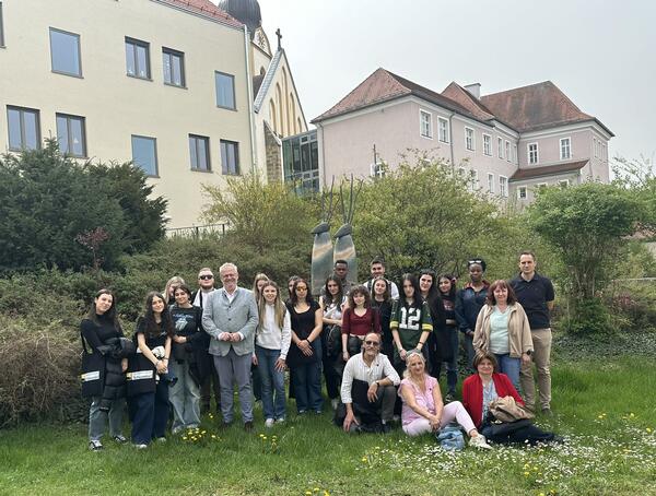 Mehrere Erwachsene und Jugendliche stehen im Freien um fotografiert zu werden. 