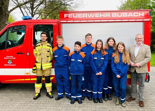 Zwei Erwachsene und sechs Kinder stehen vor einem Feuerwehrauto.