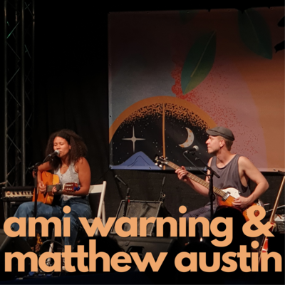 Orangene Schrift auf Foto: "Ami Warning & Matthew Austin". Die zwei 
Musiker spielen Gitarrenmusik und singen auf der Open-Air Bühne des Come Together Festivales 2021.