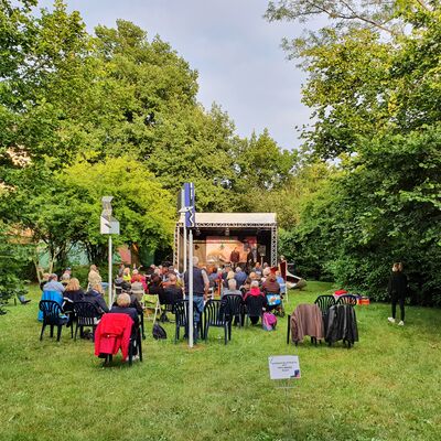 Foto vom Kebbelvillapark mit Open-Air Bühne und Besucher:innen.