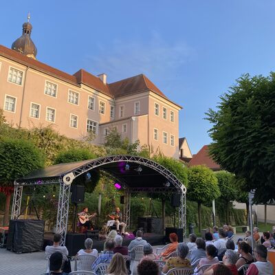 Das Publikum blickt auf das Duo "Father & Son" bestehend aus den Musikern Hans und Christoph Meier, beide mit Akustikgitarren auf der Bühne des Schwandorfer Kultursommers im Spitalgarten
