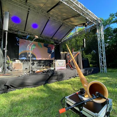 Foto von der leeren Open-Air Bühne. Sie ist mit dem Come-Together Plakat und Lichtshow dekoriert.