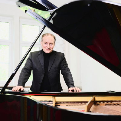 Portrait des Pianisten Christian Seibert. Er steht hinter einem geöffneten Flügel