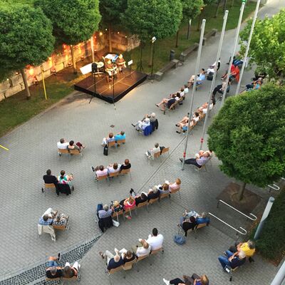 Foto: Vogelperspektive auf das Open-Air Veranstaltungsgelände des Kultursommers 2020 im Hof vor dem Rathaus Schwandorf. Zahlreiche Besucher:innen sitzen vor der erleuchteten Open-Air-Bühne.