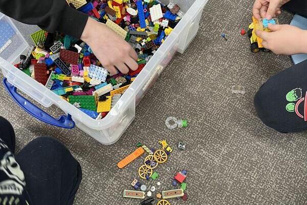 Eine Kiste voll mit LEGO-Steinen und daneben liegen auch welche auf dem Boden