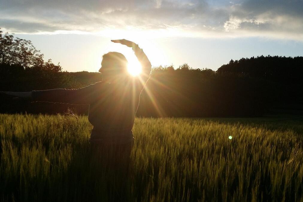Ein Mensch macht eine Übung und im Hintergrund sieht man die Sonne
