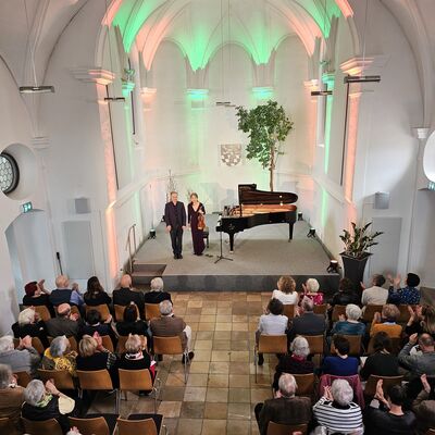 Bild vergrößern: Blick von der Galerie auf die Bühne der Spitalkirche. Der Pianist Christian Seibert und die Violinistin Jung-Won Seibert-Oh verneigen sich vor dem Publikum.