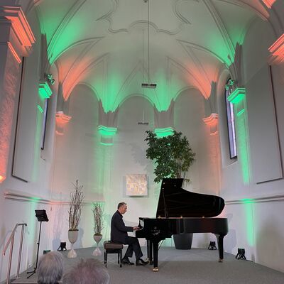 Bild vergrößern: Der Pianist Christian Seibert sitzt am Flügel auf der Bühne der Spitalkirche.