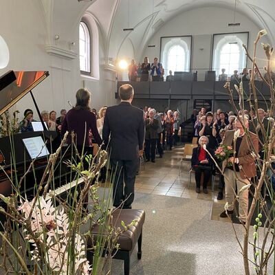Bild vergrößern: Blick von der Bühne der Spitalkirche in das Publikum. Der Pianist Christian Seiber und die Violinistin Jung-Won Seibert-Oh verneigen sich nach ihrem Konzert vor dem Publikum.