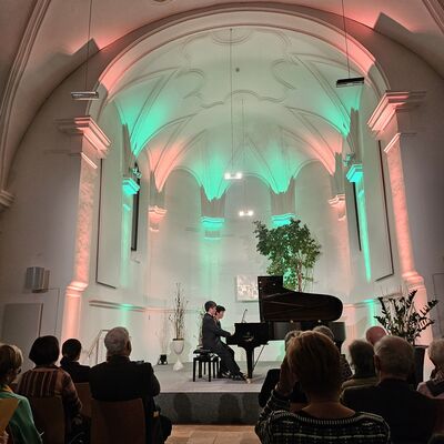 Bild vergrößern: Die beiden Pianisten Junko Tsuji und Hironobu Fuchiwaki sitzen dem Flügel auf der Bühne der Spitalkirche.