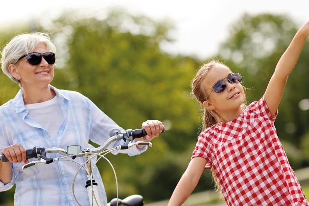 Eine ältere Frau fährt neben einem Mädchen. Beide auf dem Fahrrad